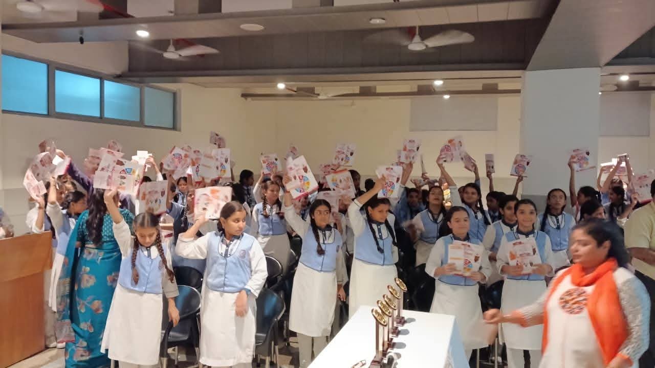School children holding certificates and folders with trophies on table